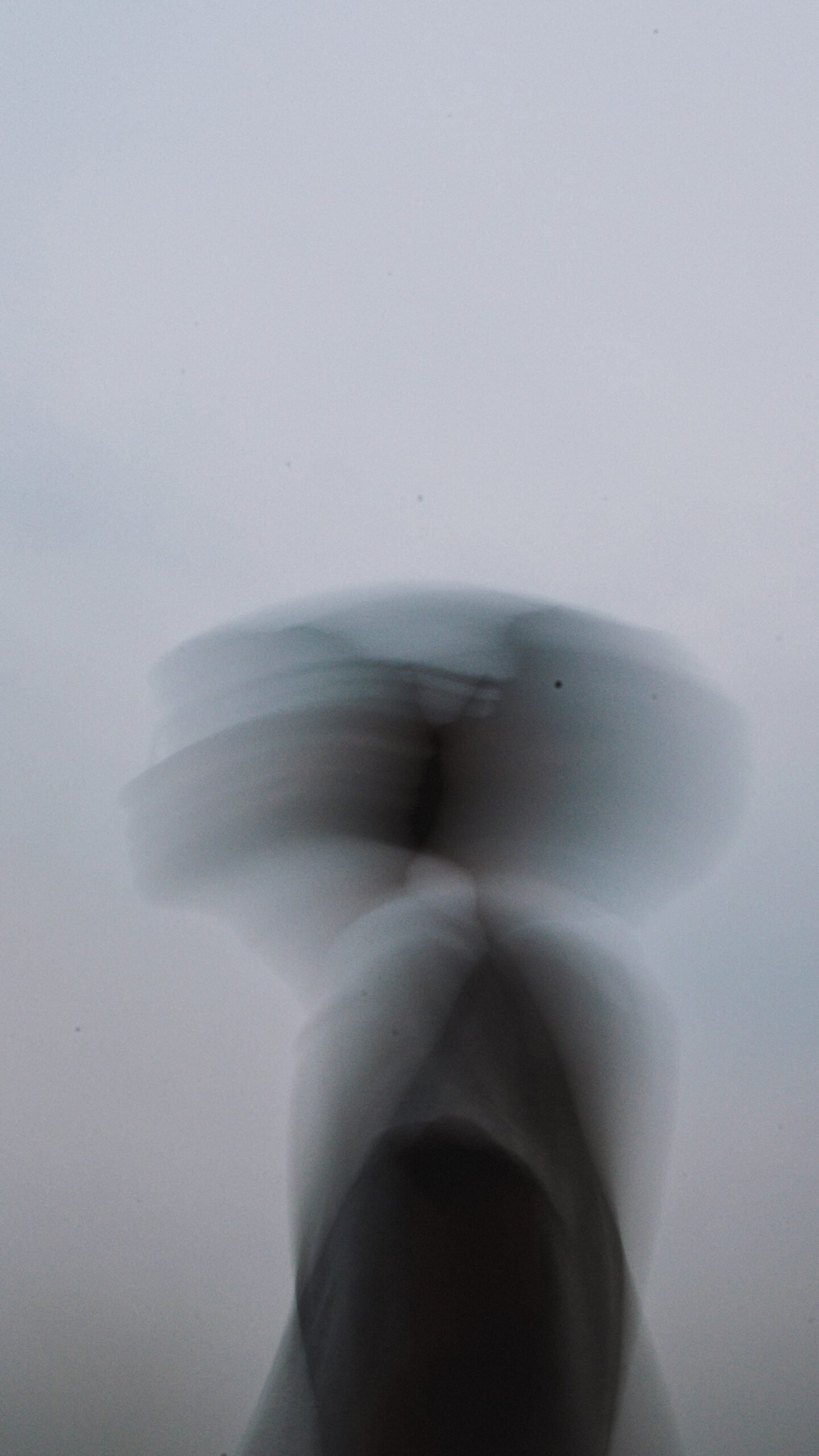 A blurred figure in a light-toned space